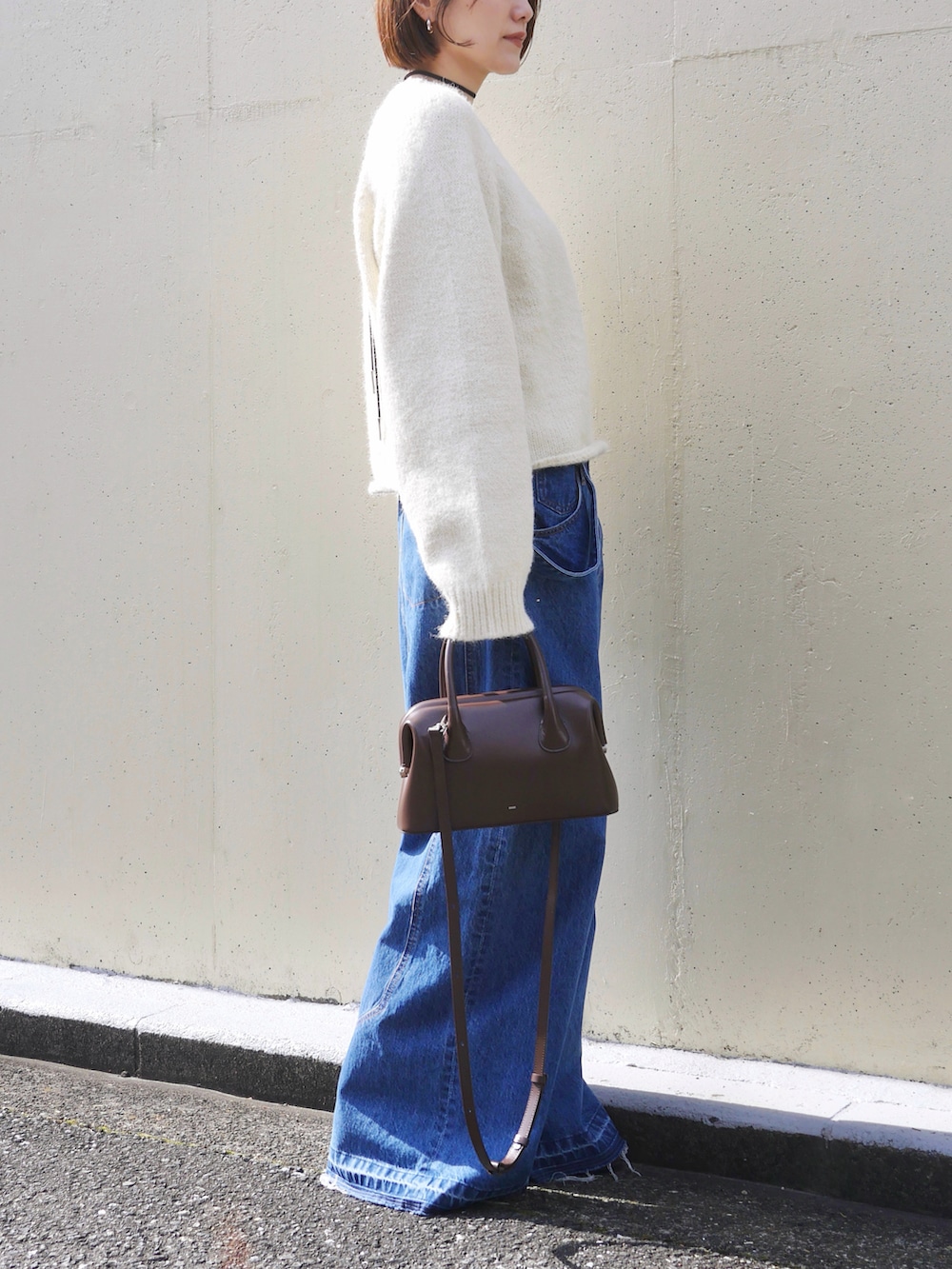 ホワイト系のニット/セーター、ブルー系のサロペット/オーバーオール、ブラウン系のショルダーバッグを着用したレディースの冬コーディネートの3枚目の写真