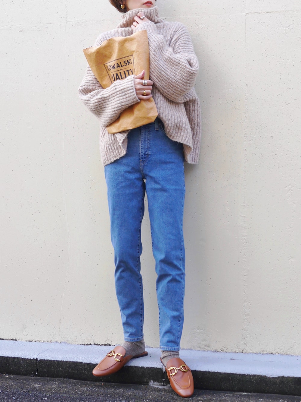 ブルー系のデニムパンツ、ブラウン系のトートバッグ、ベージュ系のニット/セーターを着用したレディースの冬コーディネートの3枚目の写真