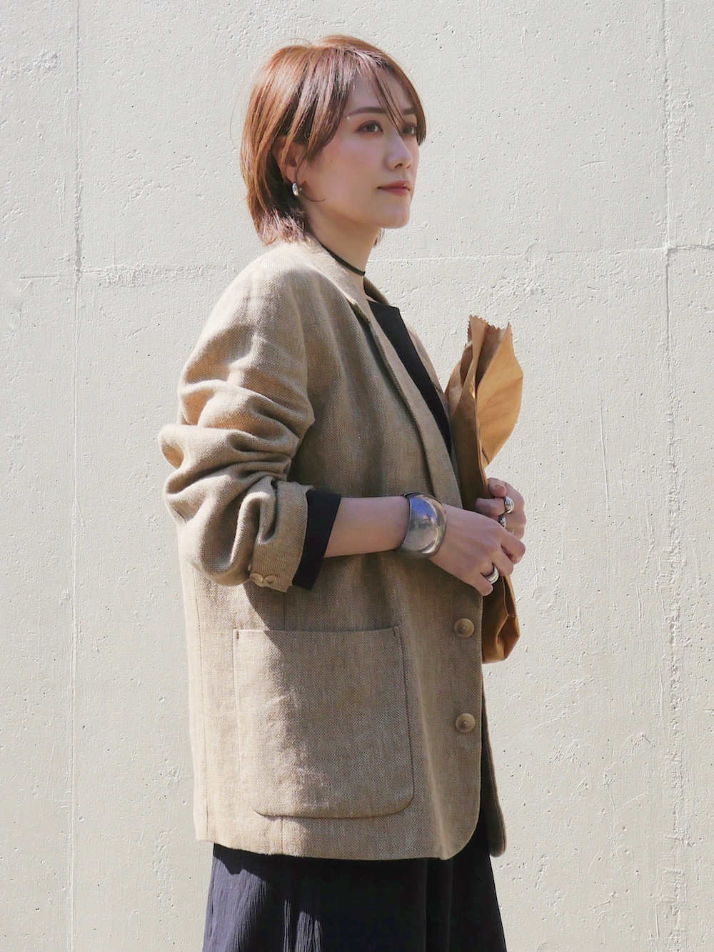 ブラック系のワンピース、ベージュ系のテーラードジャケット、ブラウン系のトートバッグを着用したレディースの春コーディネートの2枚目の写真