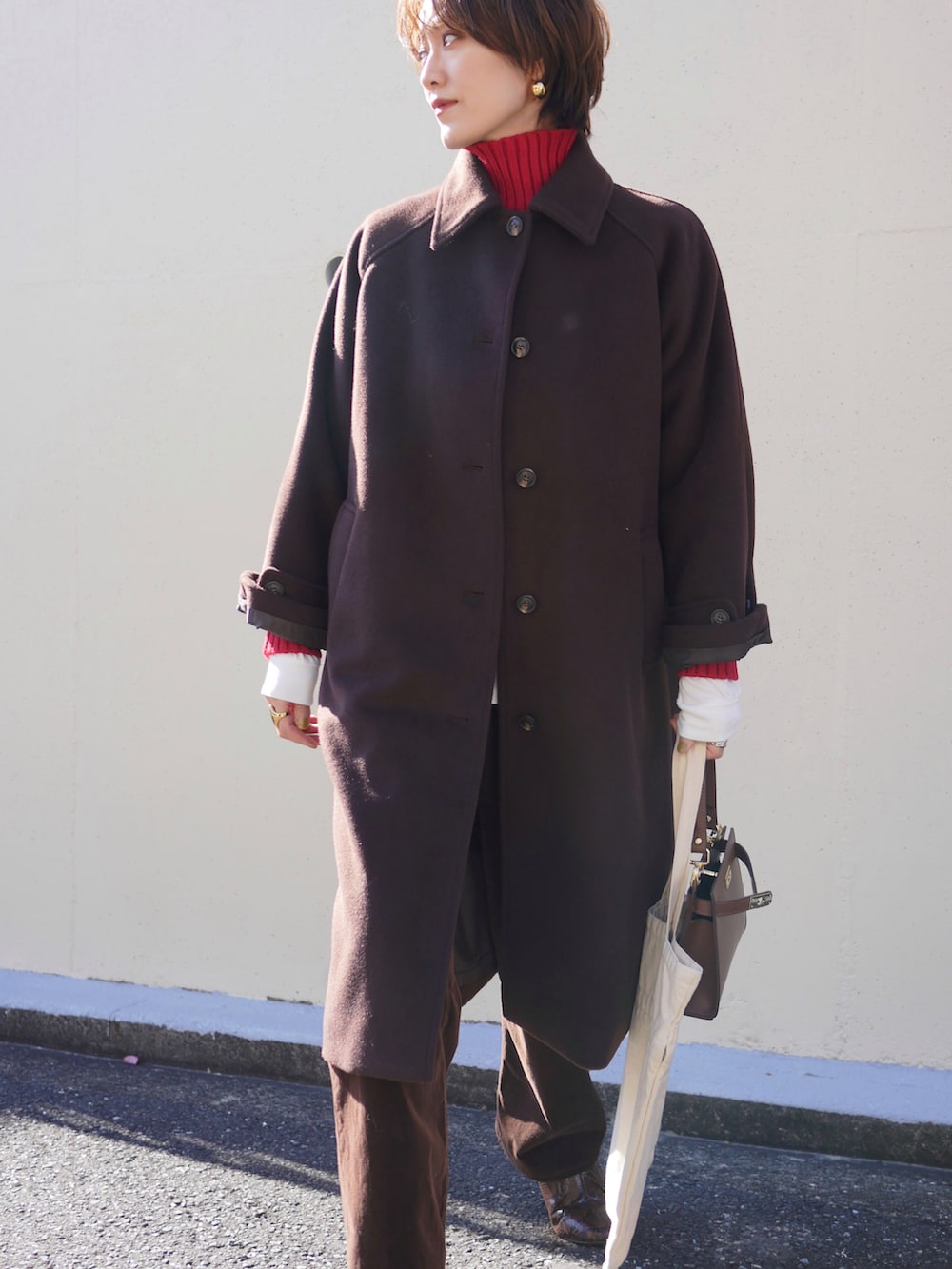 レッド系のニット/セーター、ブラウン系のショルダーバッグ、ブラウン系のステンカラーコートを着用したレディースの冬コーディネートの4枚目の写真