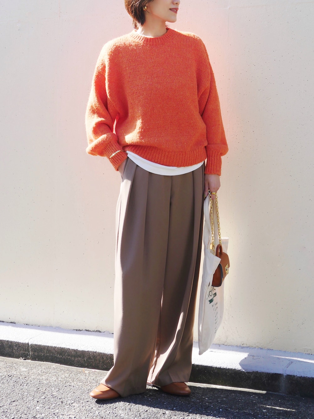 オレンジ系のニット/セーター、ベージュ系のその他パンツ、イエロー系のショルダーバッグを着用したレディースの秋コーディネートの3枚目の写真