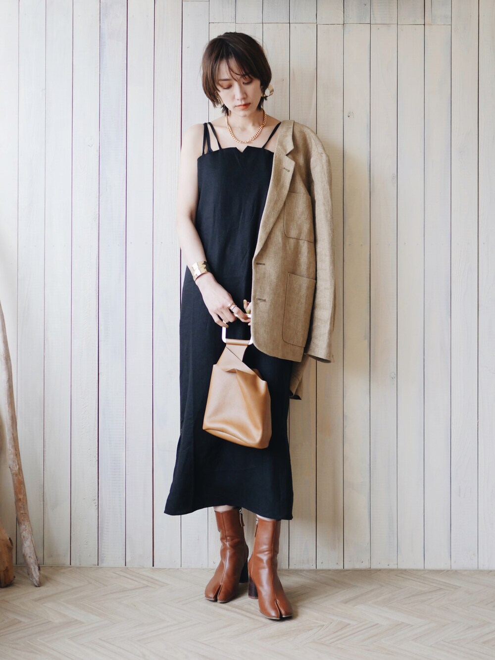 ベージュ系のテーラードジャケット、ブラック系のワンピース、ブラウン系のブーツを着用したレディースの春コーディネートの3枚目の写真