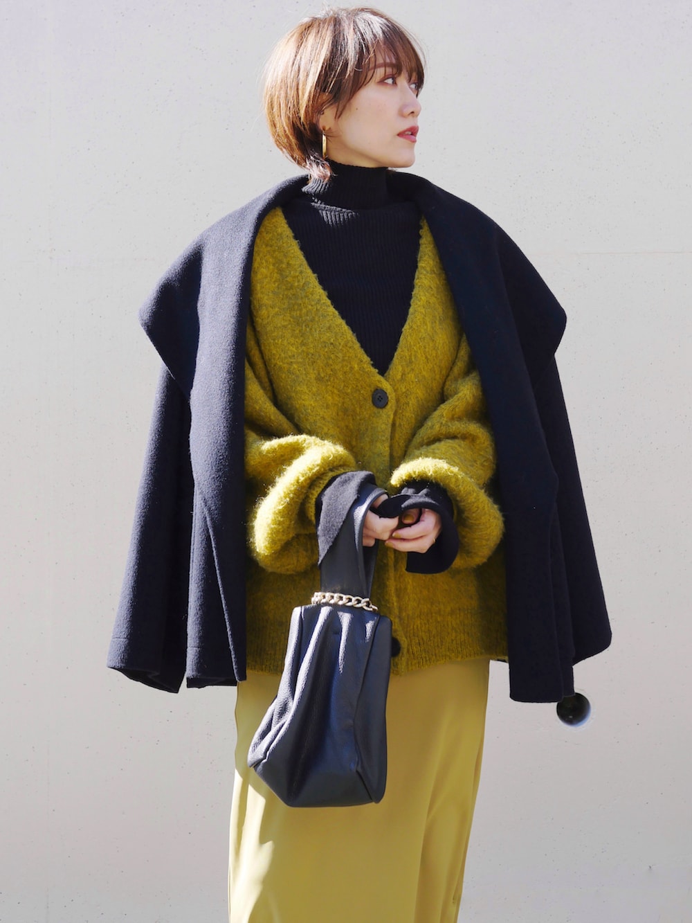ブラック系のニット/セーター、イエロー系のスカート、ブルー系のカーディガン/ボレロを着用したレディースの冬コーディネートの3枚目の写真