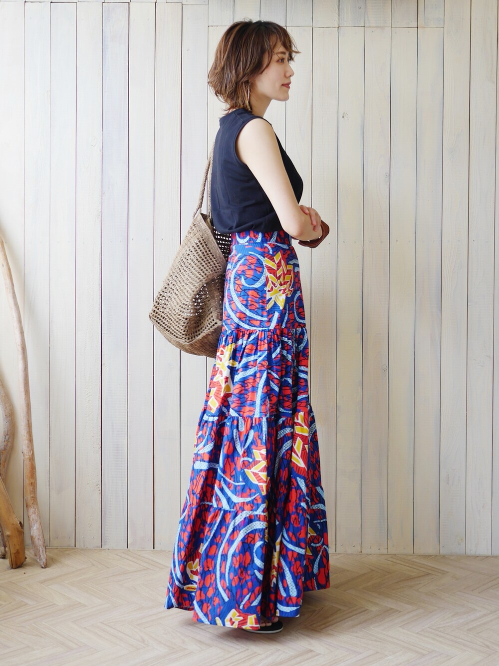 レッド系のスカート、ブラウン系のかごバッグ、その他のタンクトップを着用したレディースの夏コーディネートの4枚目の写真