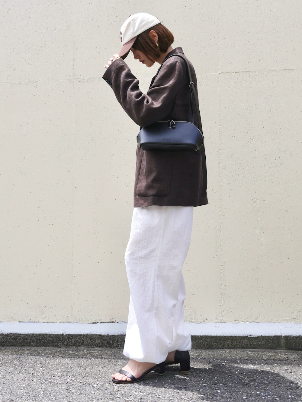 ホワイト系のその他パンツ、ブラウン系のテーラードジャケット、ブラック系のサンダルを着用したレディースの春コーディネートの2枚目の写真