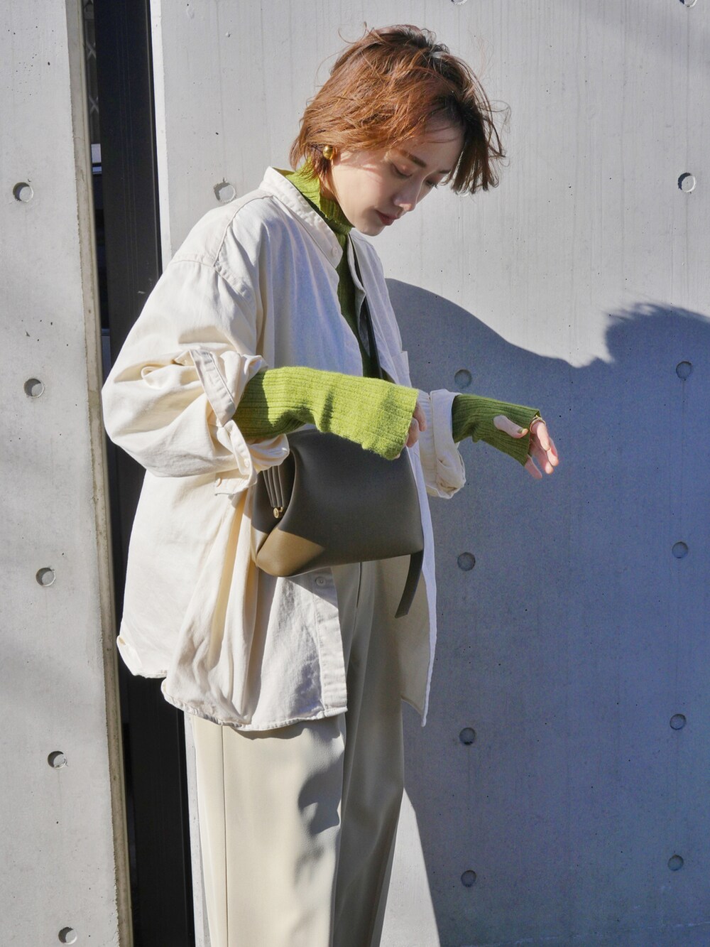 グリーン系のニット/セーター、ベージュ系のその他パンツ、ホワイト系のシャツ/ブラウスを着用したレディースの冬コーディネートの3枚目の写真