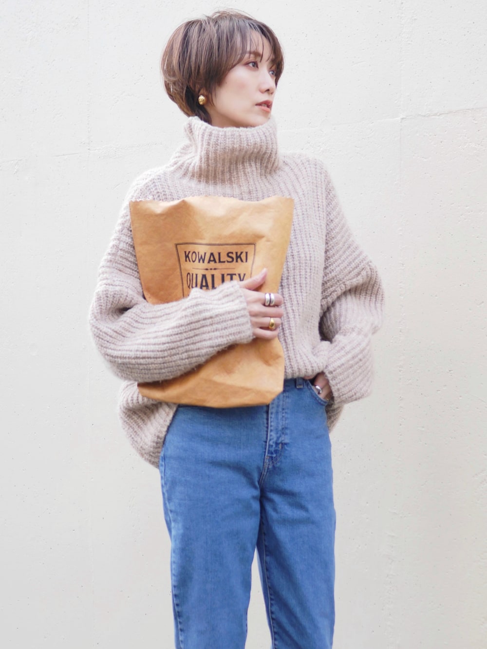 ブルー系のデニムパンツ、ブラウン系のトートバッグ、ベージュ系のニット/セーターを着用したレディースの冬コーディネートの2枚目の写真