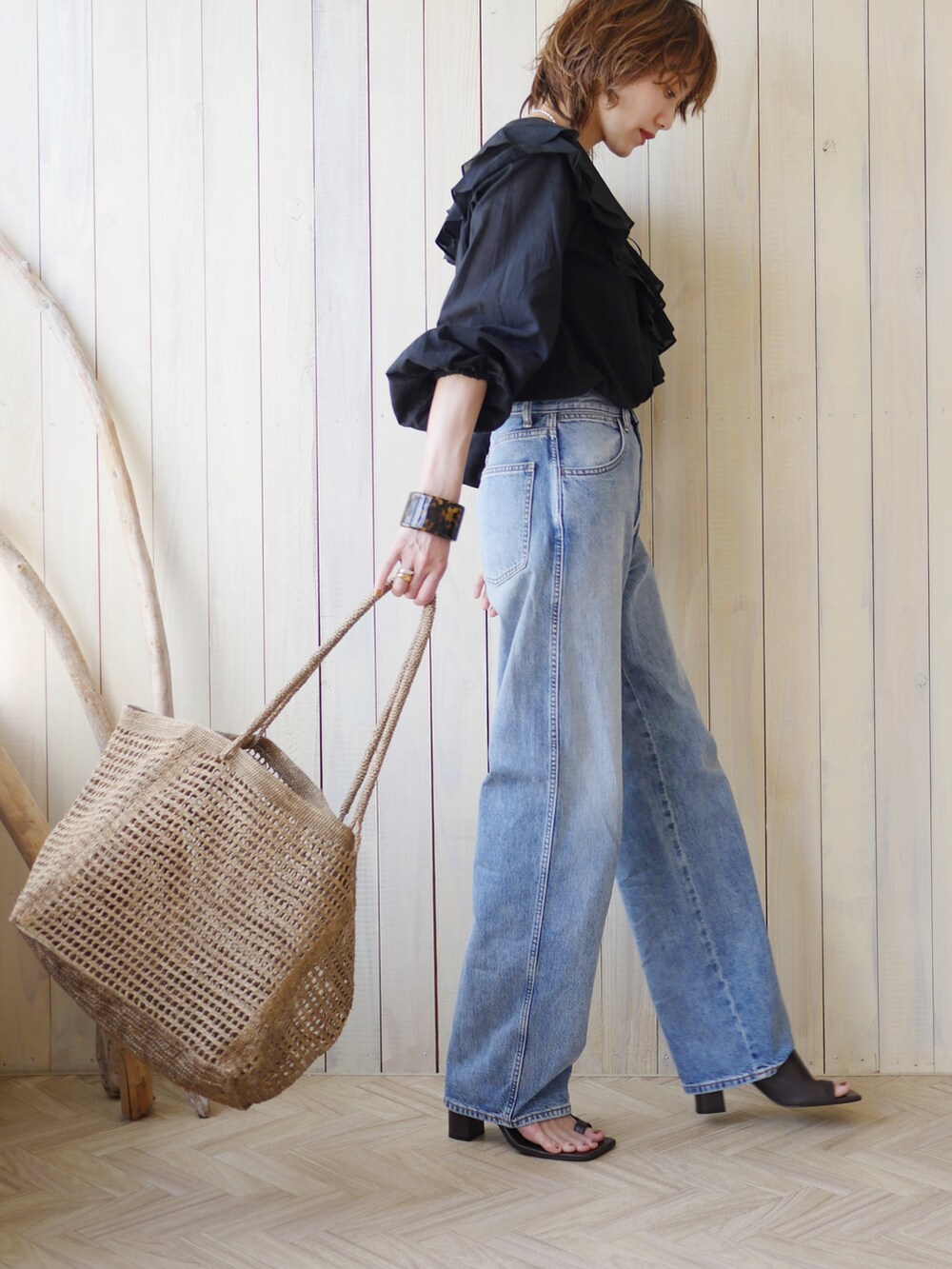 ブラック系のシャツ/ブラウス、ブラウン系のかごバッグ、ブルー系のデニムパンツを着用したレディースの夏コーディネートの3枚目の写真
