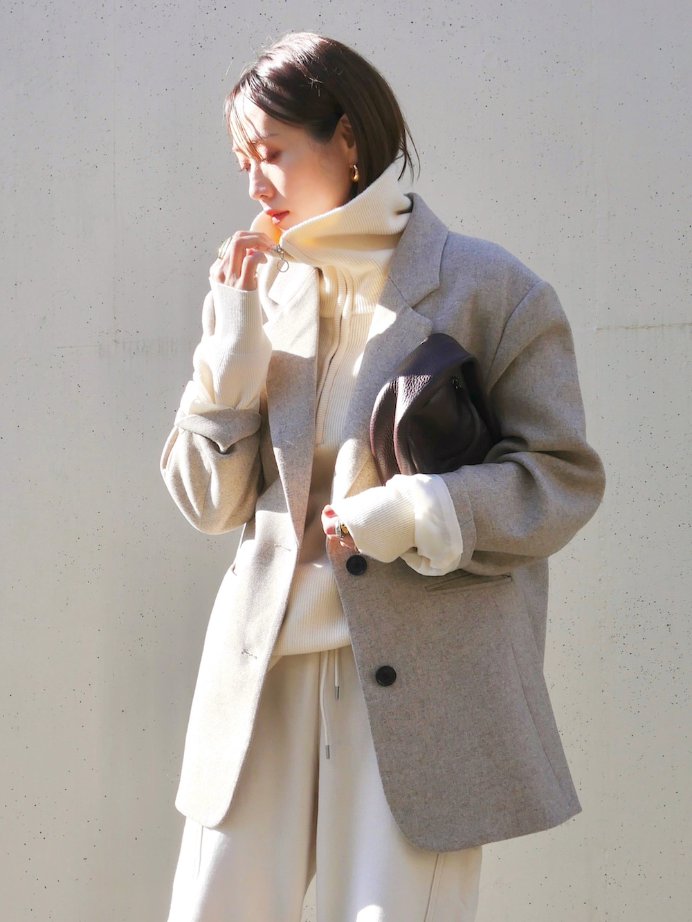 ベージュ系のテーラードジャケット、レッド系のハンドバッグ、ホワイト系のスニーカーを着用したレディースの冬コーディネートの5枚目の写真