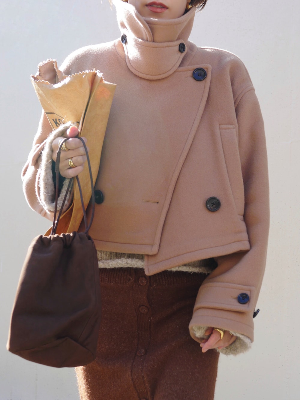 ベージュ系のピーコート、ブラウン系のスカート、ブラウン系のトートバッグを着用したレディースの冬コーディネートの5枚目の写真
