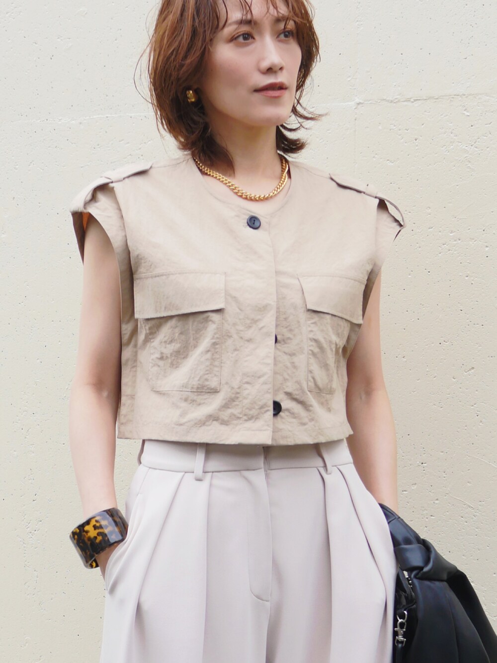 ホワイト系のその他パンツ、ベージュ系のベスト、ブラック系のショルダーバッグを着用したレディースの夏コーディネートの2枚目の写真