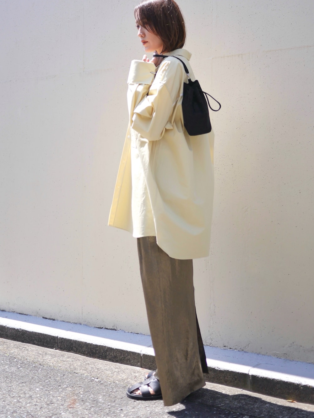 イエロー系のシャツ/ブラウス、ゴールド系のスカート、ブラック系のサンダルを着用したレディースの春コーディネートの2枚目の写真