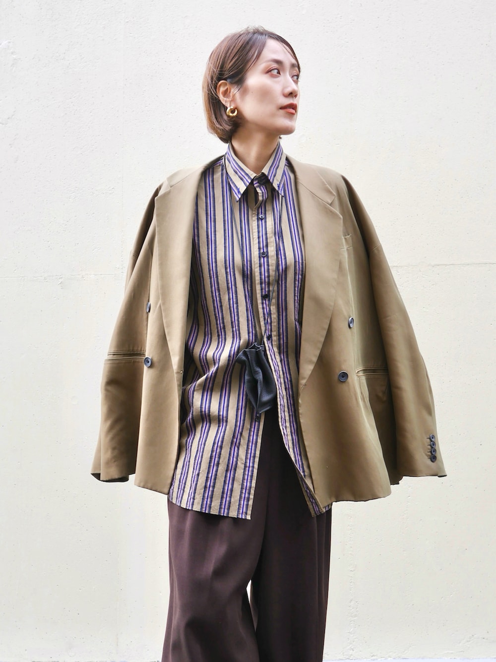 グリーン系のテーラードジャケット、ブラウン系のスラックス、ブラウン系のローファーを着用したレディースの秋コーディネートの2枚目の写真