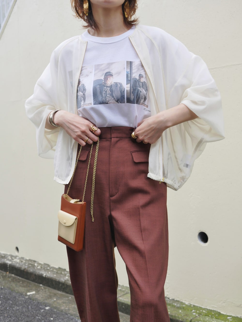 レッド系のスラックス、ホワイト系のTシャツ/カットソー、ブラウン系のサンダルを着用したレディースの春コーディネートの3枚目の写真