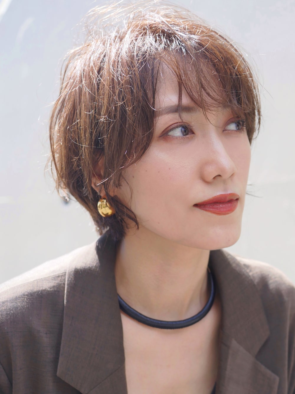 ゴールド系のスカート、ブラウン系のテーラードジャケット、ブラック系のタンクトップを着用したレディースの秋コーディネートの2枚目の写真