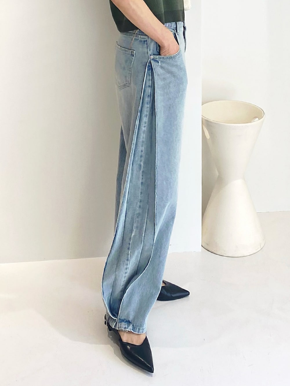 ブルー系のデニムパンツ、グリーン系のトップス、ゴールド系のピアス（両耳用）を着用したレディースの春コーディネートの2枚目の写真