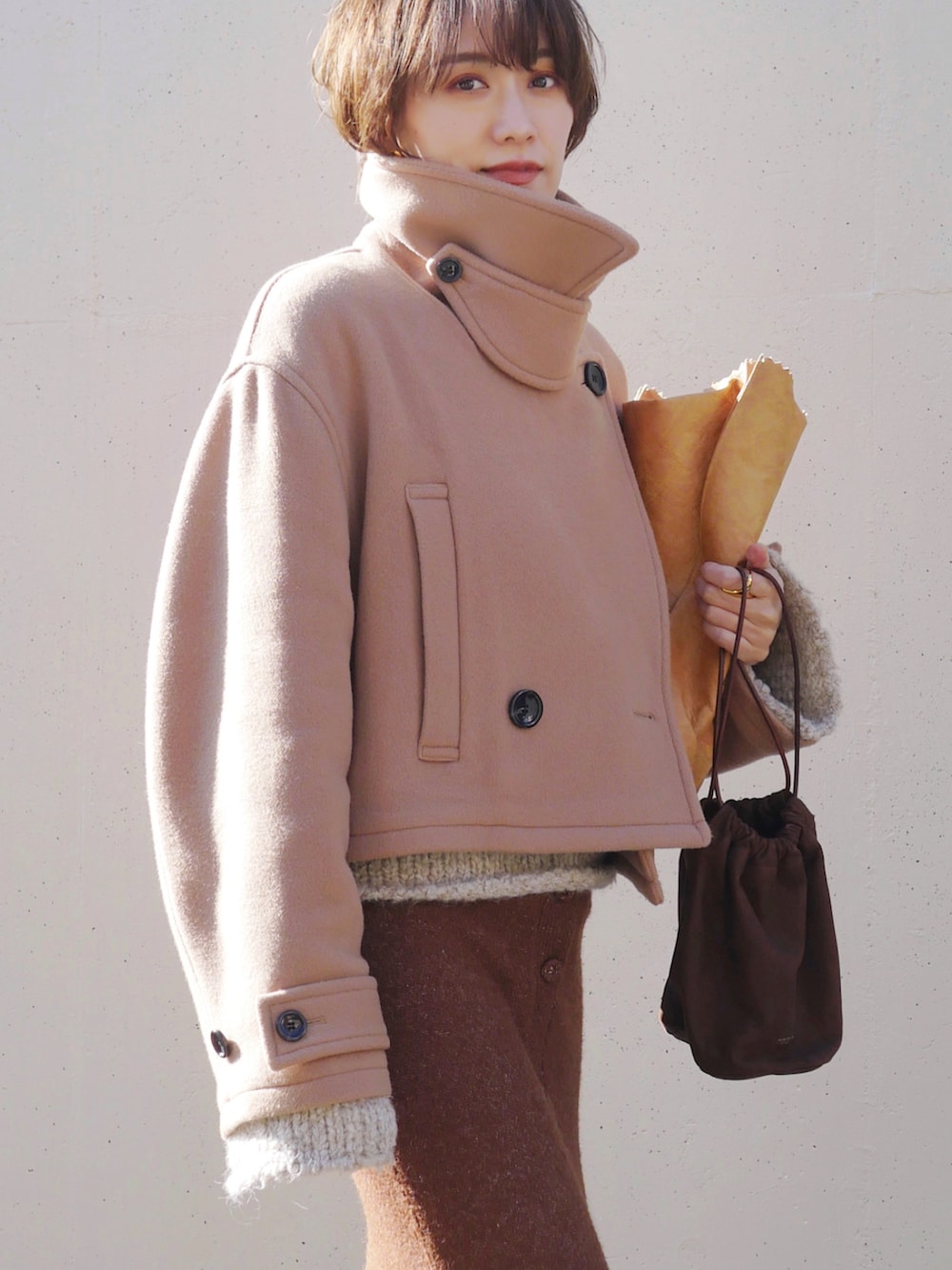 ベージュ系のピーコート、ブラウン系のスカート、ブラウン系のトートバッグを着用したレディースの冬コーディネートの3枚目の写真