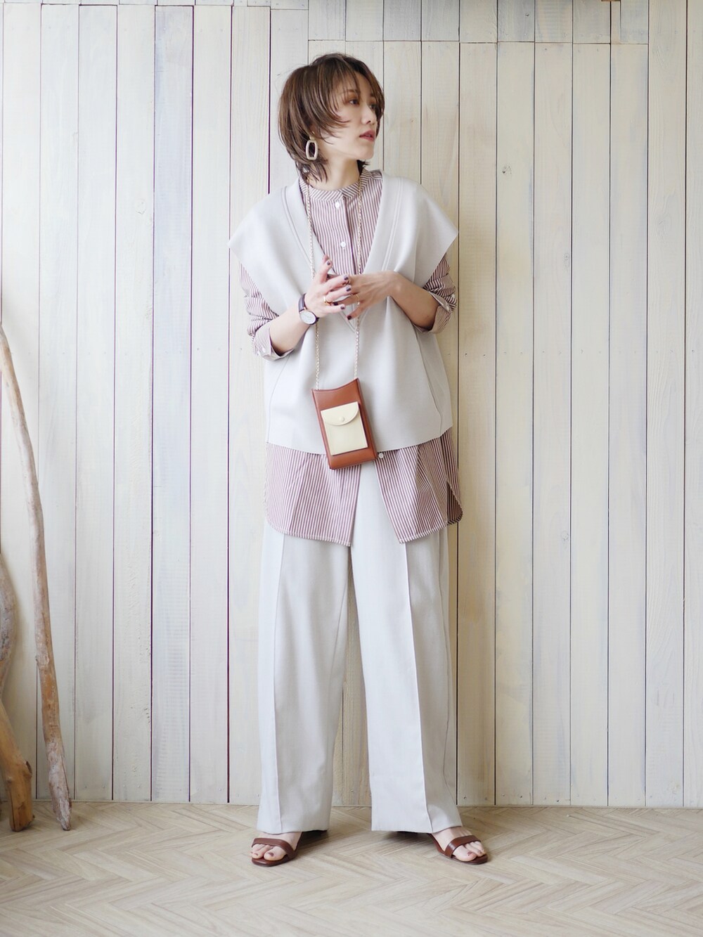 ブラウン系のシャツ/ブラウス、グレー系のベスト、ホワイト系のスラックスを着用したレディースの春コーディネートの2枚目の写真