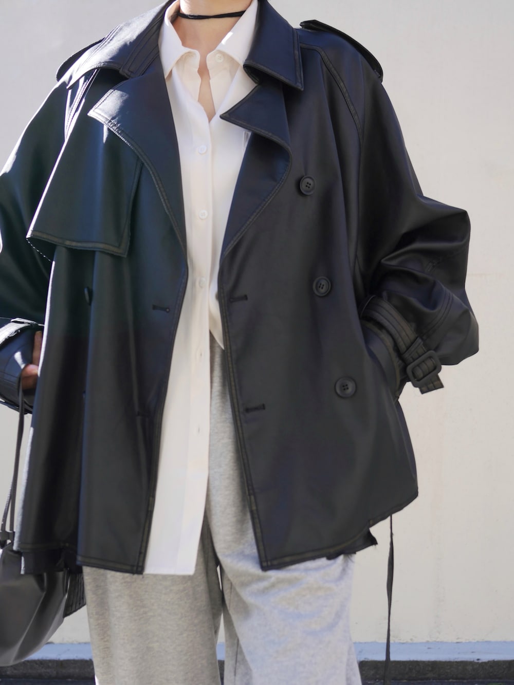 ブラック系のトレンチコート、グレー系のスウェットパンツ、ホワイト系のシャツ/ブラウスを着用したレディースの冬コーディネートの2枚目の写真