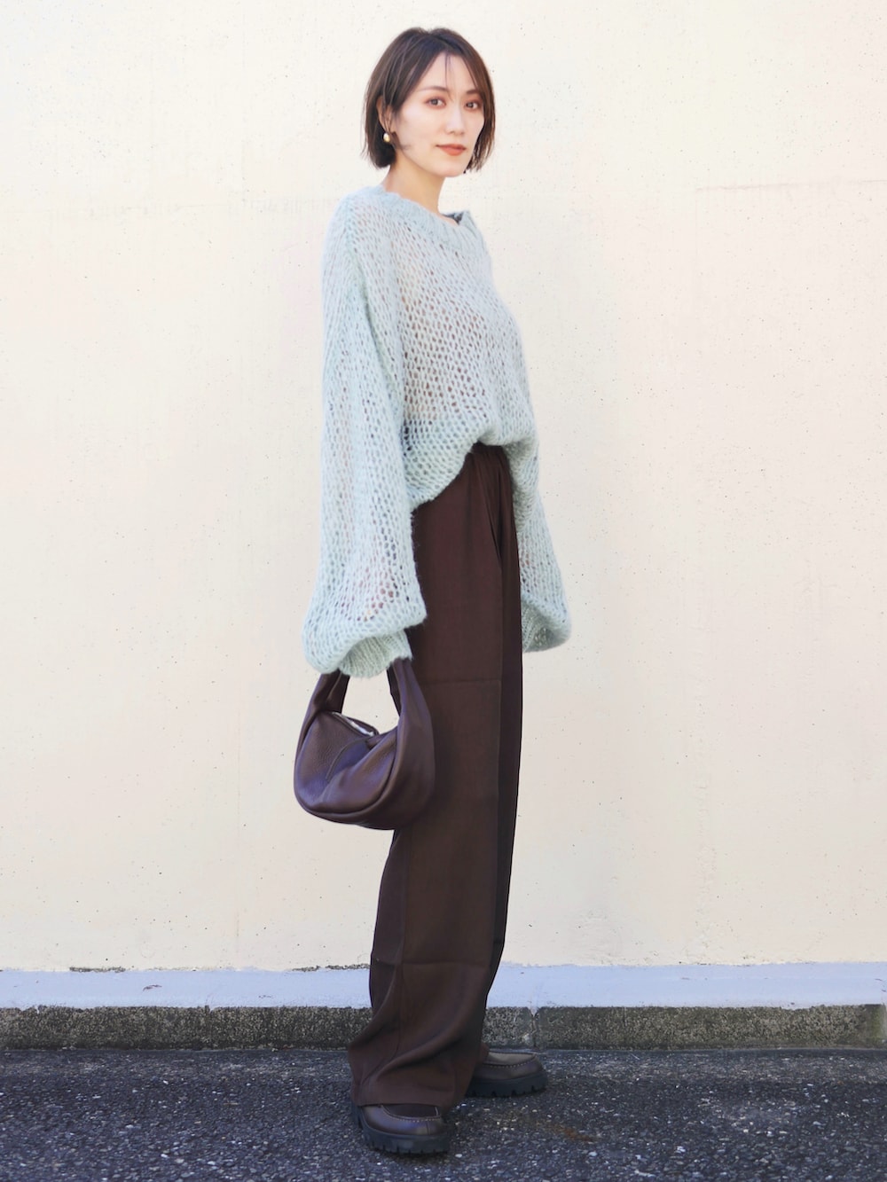 グリーン系のニット/セーター、ブラウン系のスラックス、レッド系のハンドバッグを着用したレディースの秋コーディネートの2枚目の写真