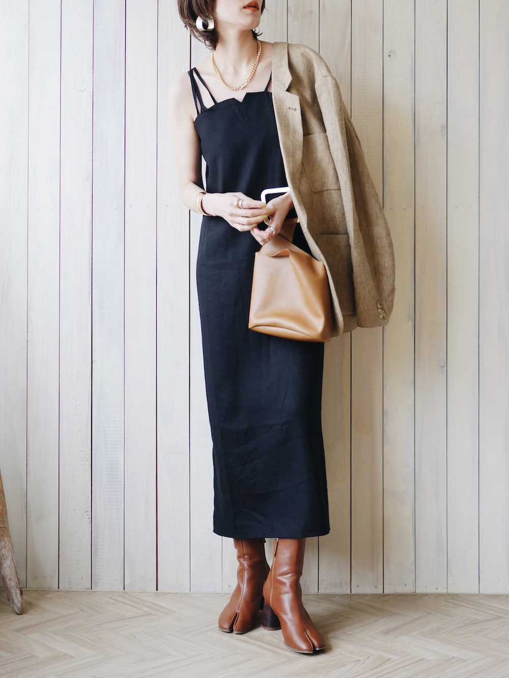 ベージュ系のテーラードジャケット、ブラック系のワンピース、ブラウン系のブーツを着用したレディースの春コーディネートの4枚目の写真