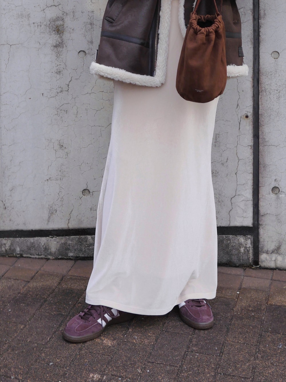 ブラウン系のライダースジャケット、ホワイト系のスカート、ブラウン系のスニーカーを着用したレディースの冬コーディネートの5枚目の写真