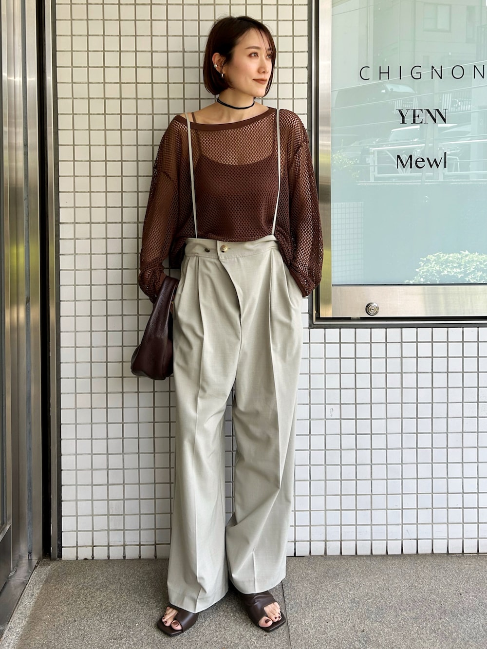 ブラウン系のTシャツ/カットソー、ベージュ系のスラックス、レッド系のハンドバッグを着用したレディースの春コーディネートの3枚目の写真