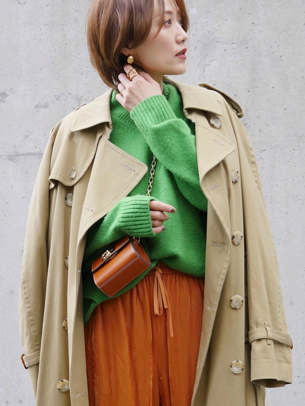 グリーン系のニット/セーター、オレンジ系のその他パンツ、ベージュ系のトレンチコートを着用したレディースの冬コーディネートの4枚目の写真