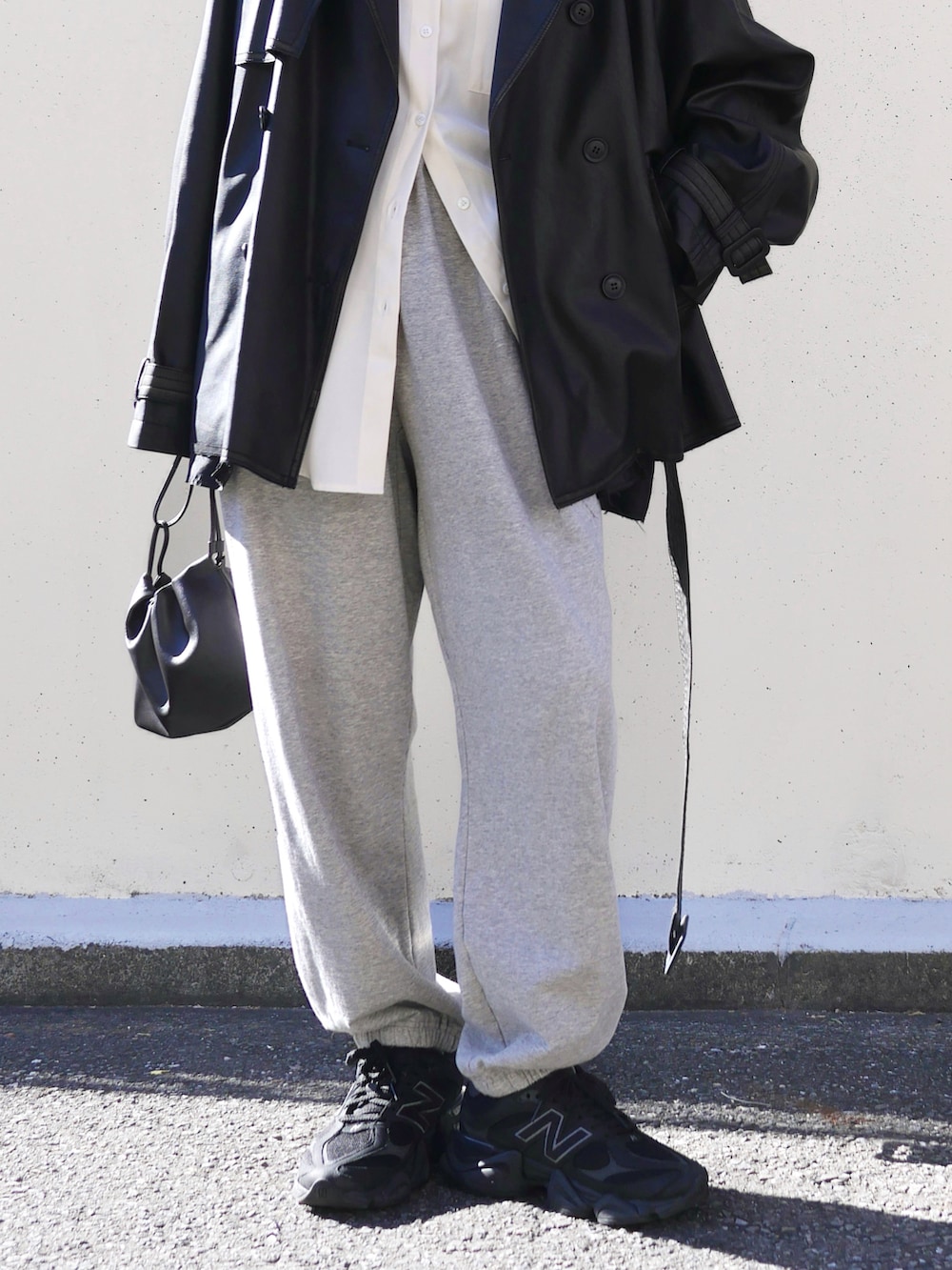 ブラック系のトレンチコート、グレー系のスウェットパンツ、ホワイト系のシャツ/ブラウスを着用したレディースの冬コーディネートの4枚目の写真