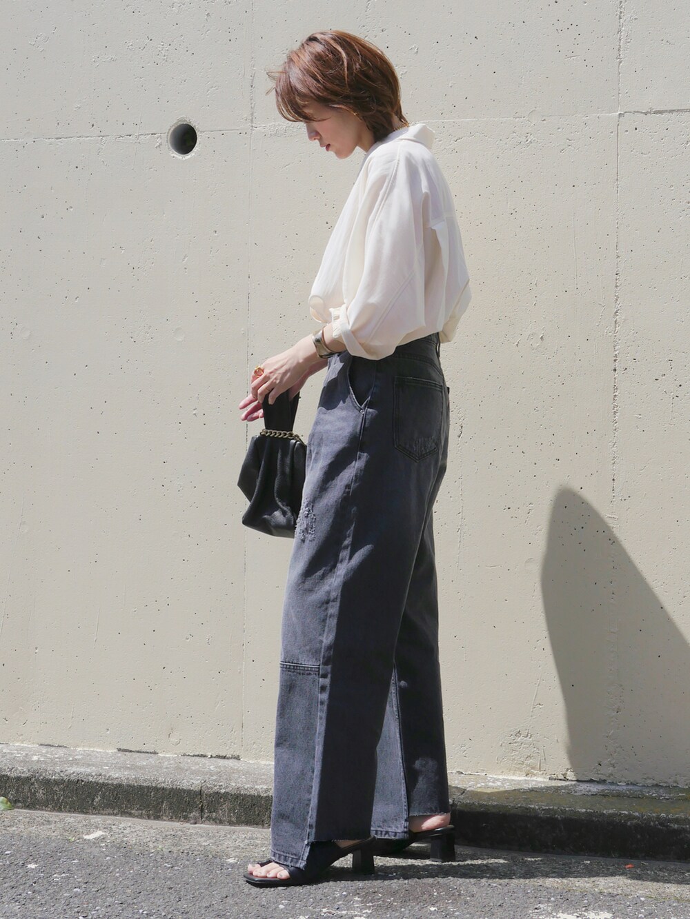 グレー系のデニムパンツ、ホワイト系のテーラードジャケット、ブラック系のサンダルを着用したレディースの春コーディネートの3枚目の写真