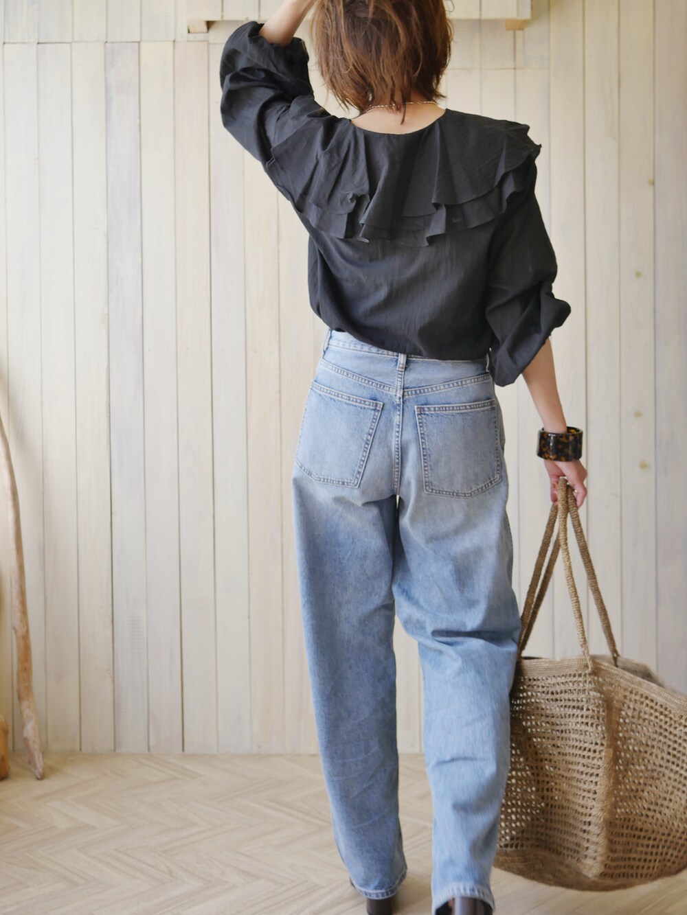 ブラック系のシャツ/ブラウス、ブラウン系のかごバッグ、ブルー系のデニムパンツを着用したレディースの夏コーディネートの4枚目の写真