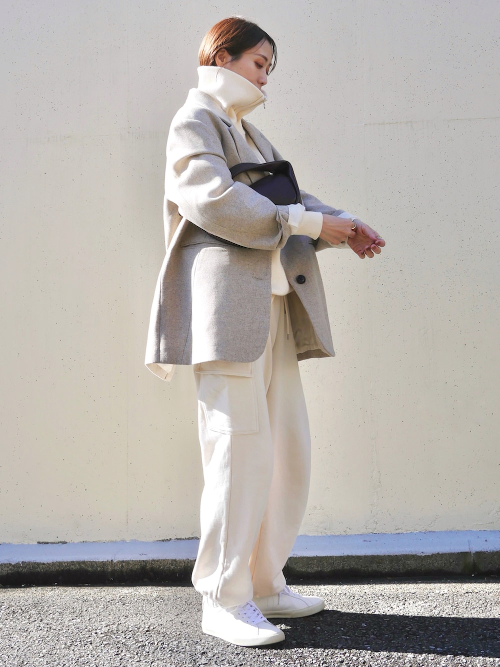 ベージュ系のテーラードジャケット、レッド系のハンドバッグ、ホワイト系のスニーカーを着用したレディースの冬コーディネートの3枚目の写真