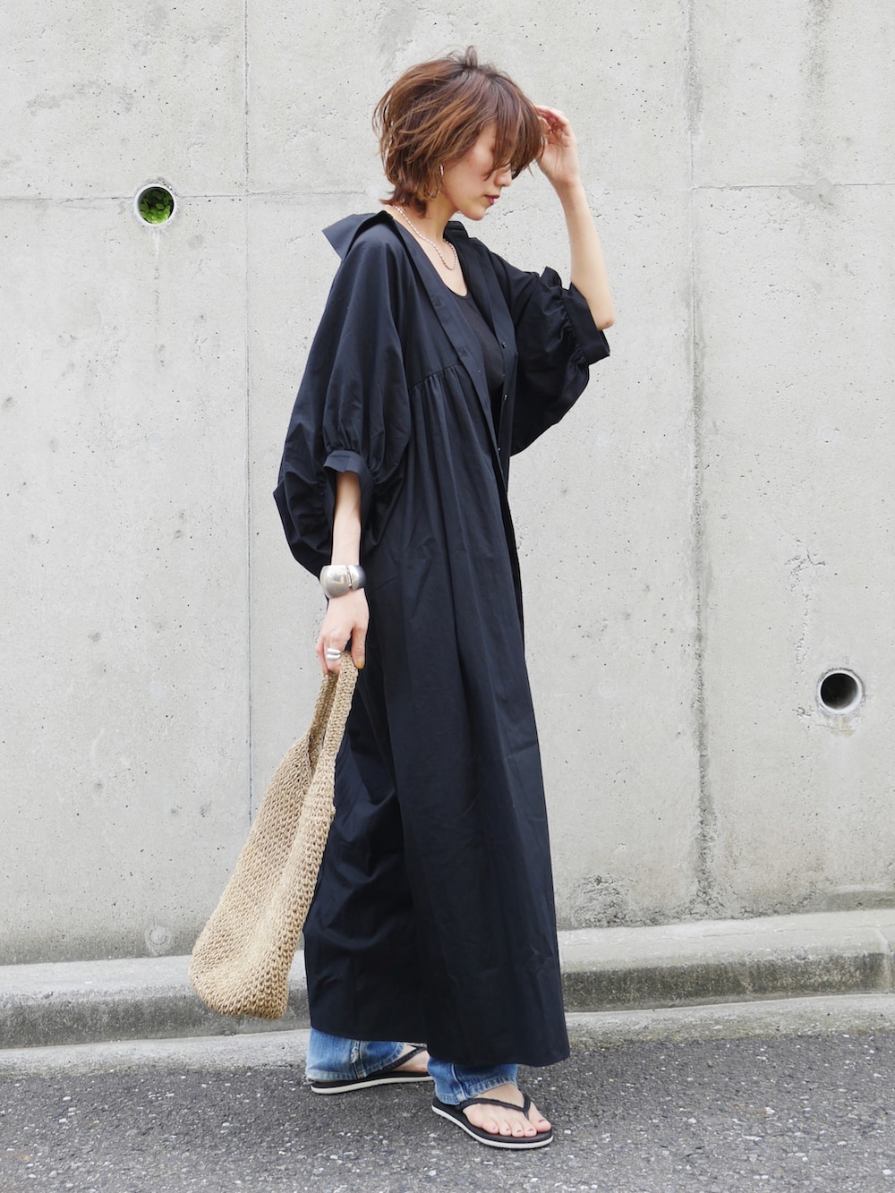 ブラック系のワンピース、ブラック系のサンダル、ベージュ系のトートバッグを着用したレディースの夏コーディネートの4枚目の写真