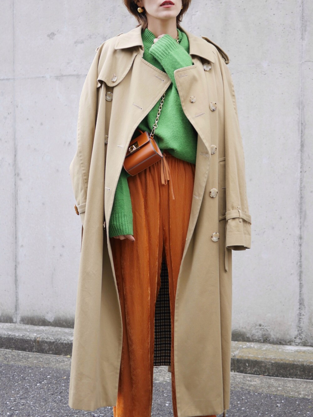 グリーン系のニット/セーター、オレンジ系のその他パンツ、ベージュ系のトレンチコートを着用したレディースの冬コーディネートの3枚目の写真