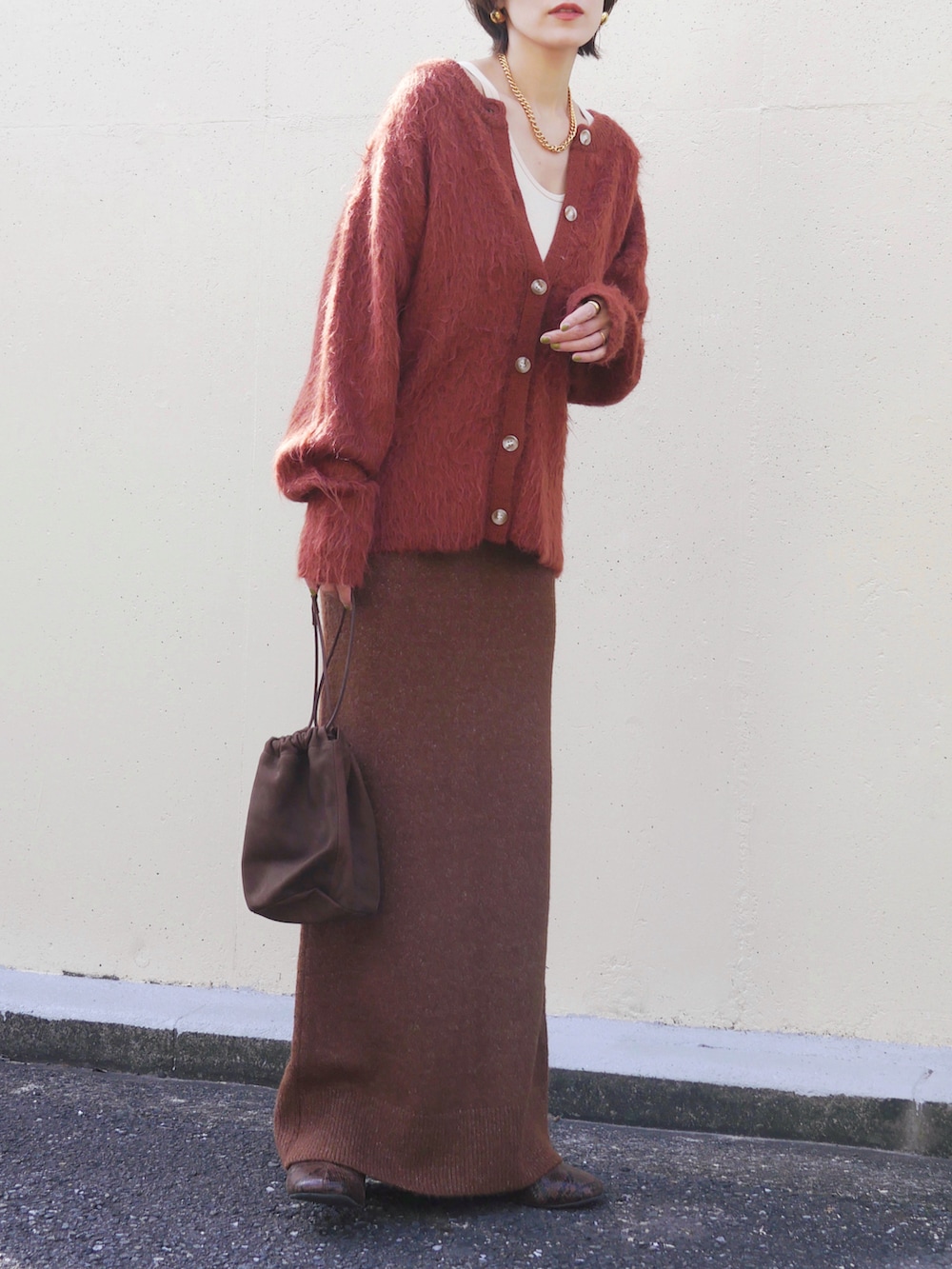 オレンジ系のカーディガン/ボレロ、ブラウン系のスカート、ブラウン系のトートバッグを着用したレディースの冬コーディネートの3枚目の写真