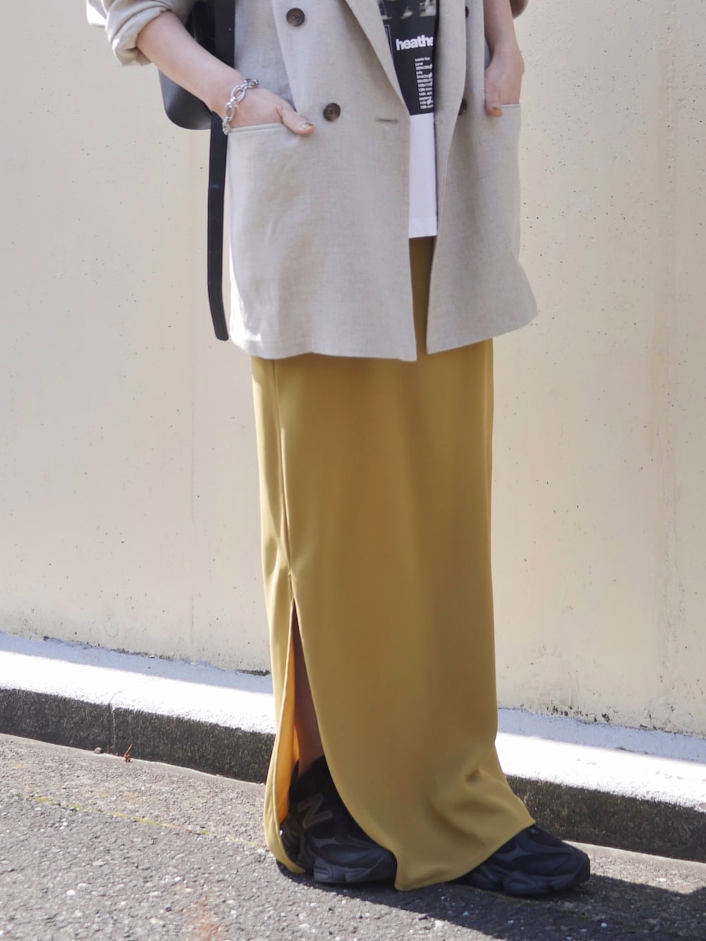 ホワイト系のTシャツ/カットソー、イエロー系のスカート、ブラック系のショルダーバッグを着用したレディースの春コーディネートの3枚目の写真