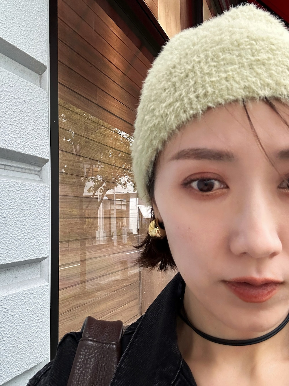 ブラック系のデニムジャケット、レッド系のハンドバッグ、ブラウン系のスラックスを着用したレディースの秋コーディネートの3枚目の写真