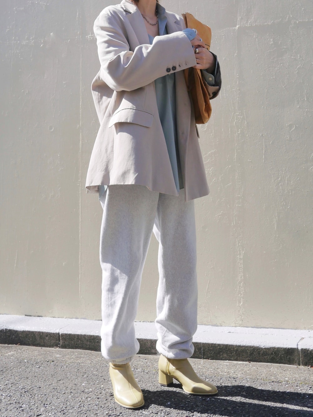 グレー系のスウェットパンツ、イエロー系のブーツ、ブラウン系のトートバッグを着用したレディースの春コーディネートの3枚目の写真