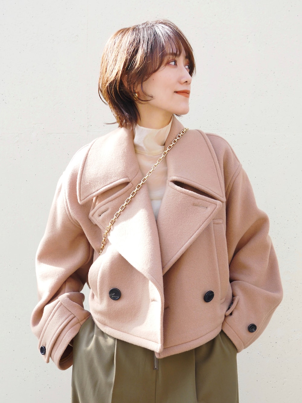 ベージュ系のピーコート、グリーン系のサロペット/オーバーオール、ベージュ系のシャツ/ブラウスを着用したレディースの秋コーディネートの2枚目の写真