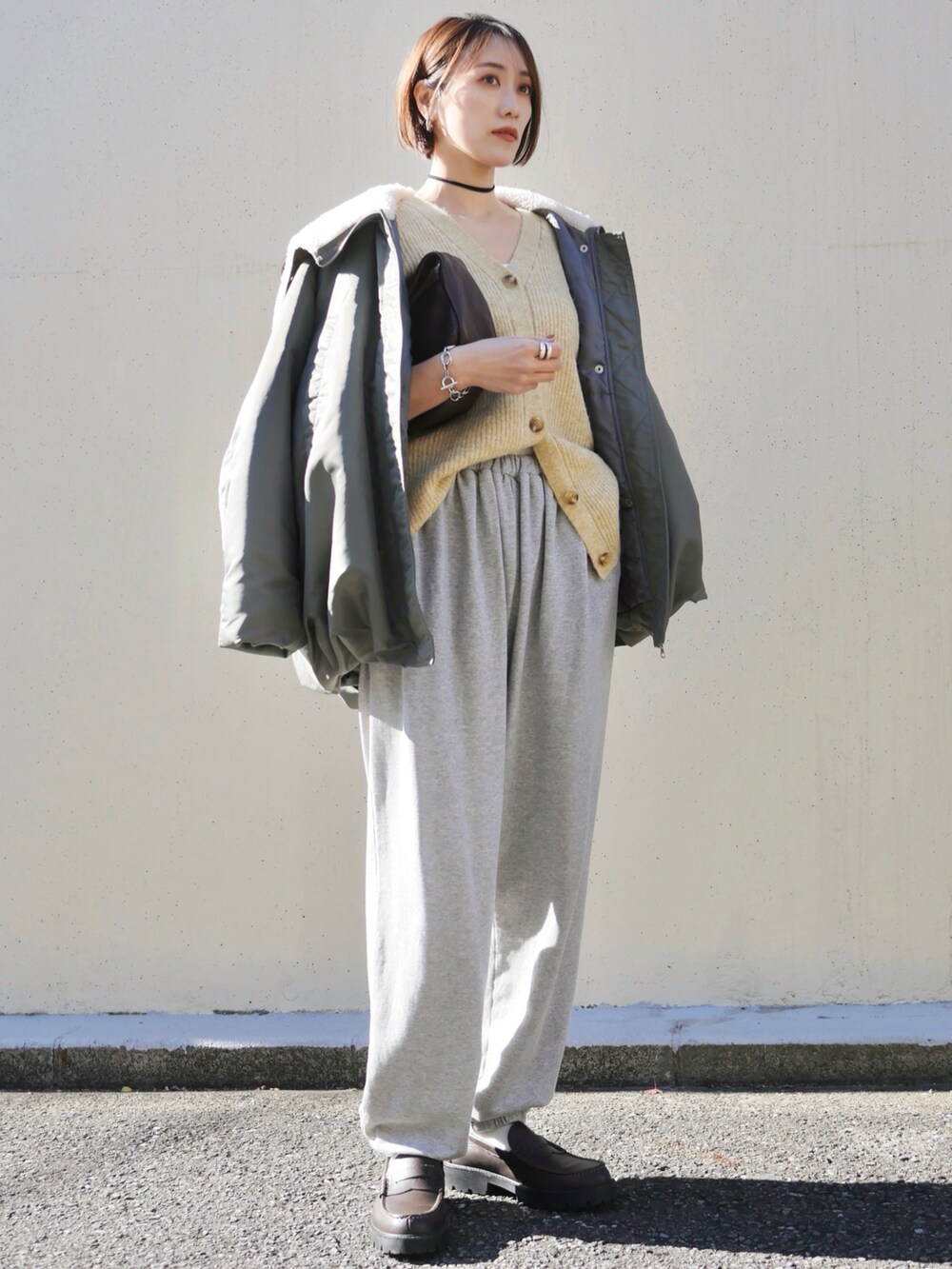 イエロー系のカーディガン/ボレロ、グリーン系のブルゾン、グレー系のスウェットパンツを着用したレディースの冬コーディネートの2枚目の写真