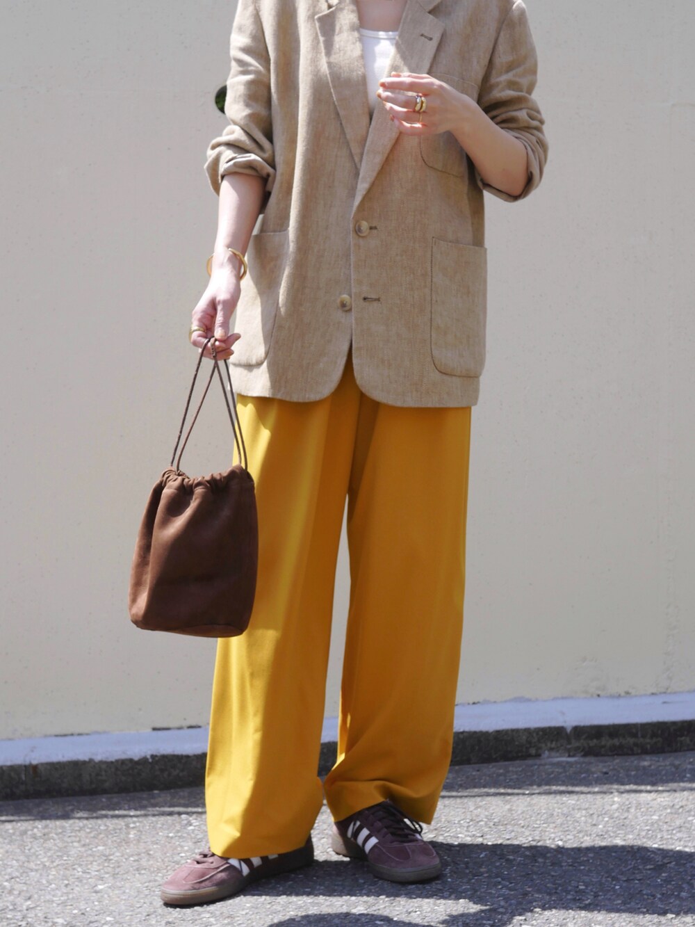 ベージュ系のテーラードジャケット、イエロー系のその他パンツ、ブラウン系のスニーカーを着用したレディースの春コーディネートの5枚目の写真