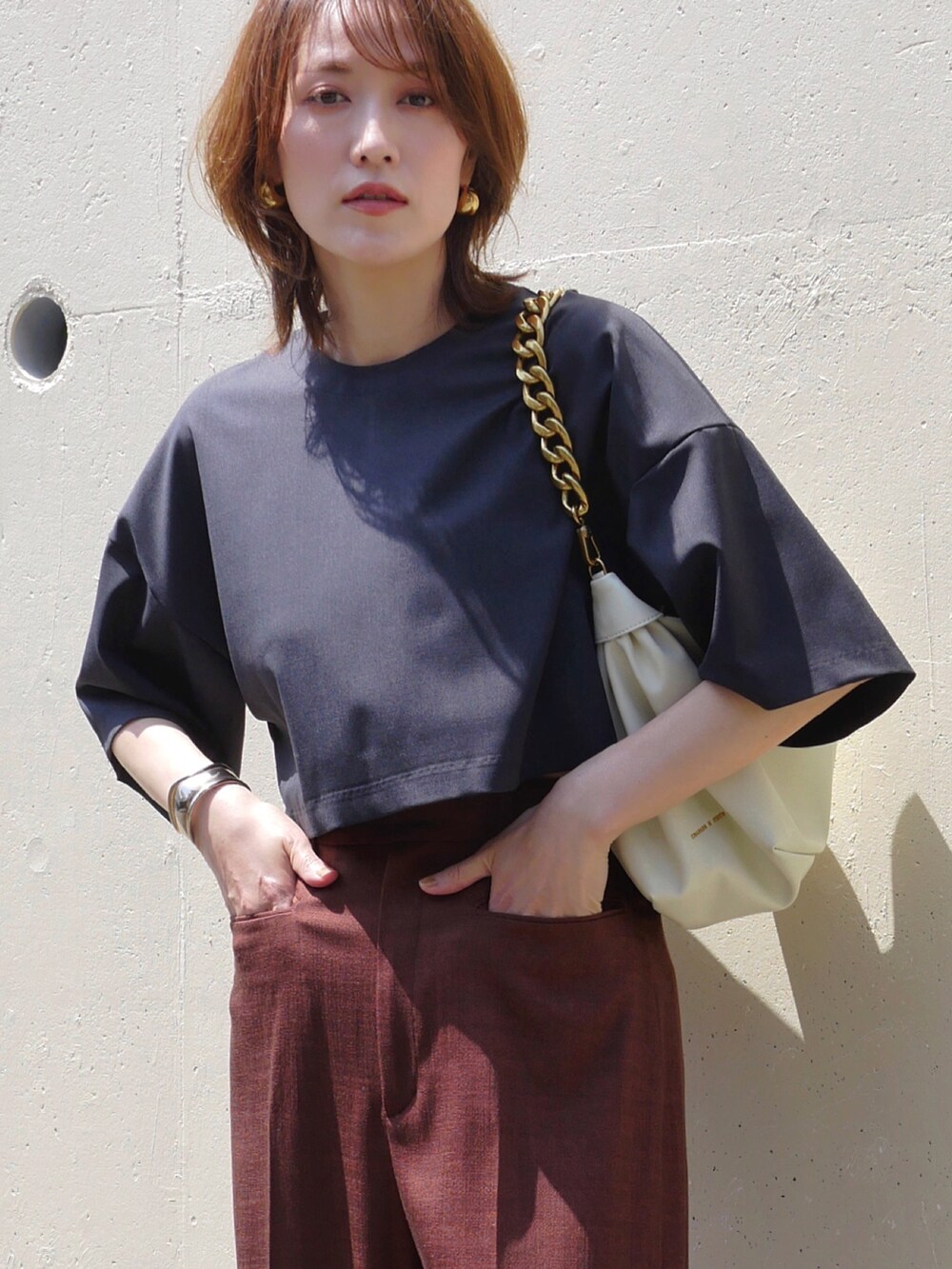 レッド系のスラックス、ホワイト系のショルダーバッグ、ブラック系のTシャツ/カットソーを着用したレディースの春コーディネートの2枚目の写真