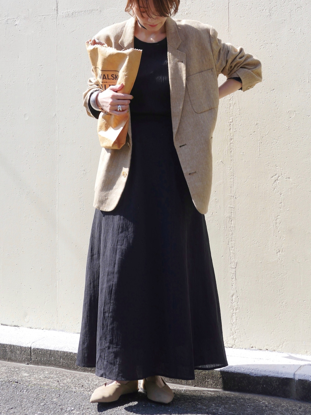 ブラック系のワンピース、ベージュ系のテーラードジャケット、ブラウン系のトートバッグを着用したレディースの春コーディネートの4枚目の写真