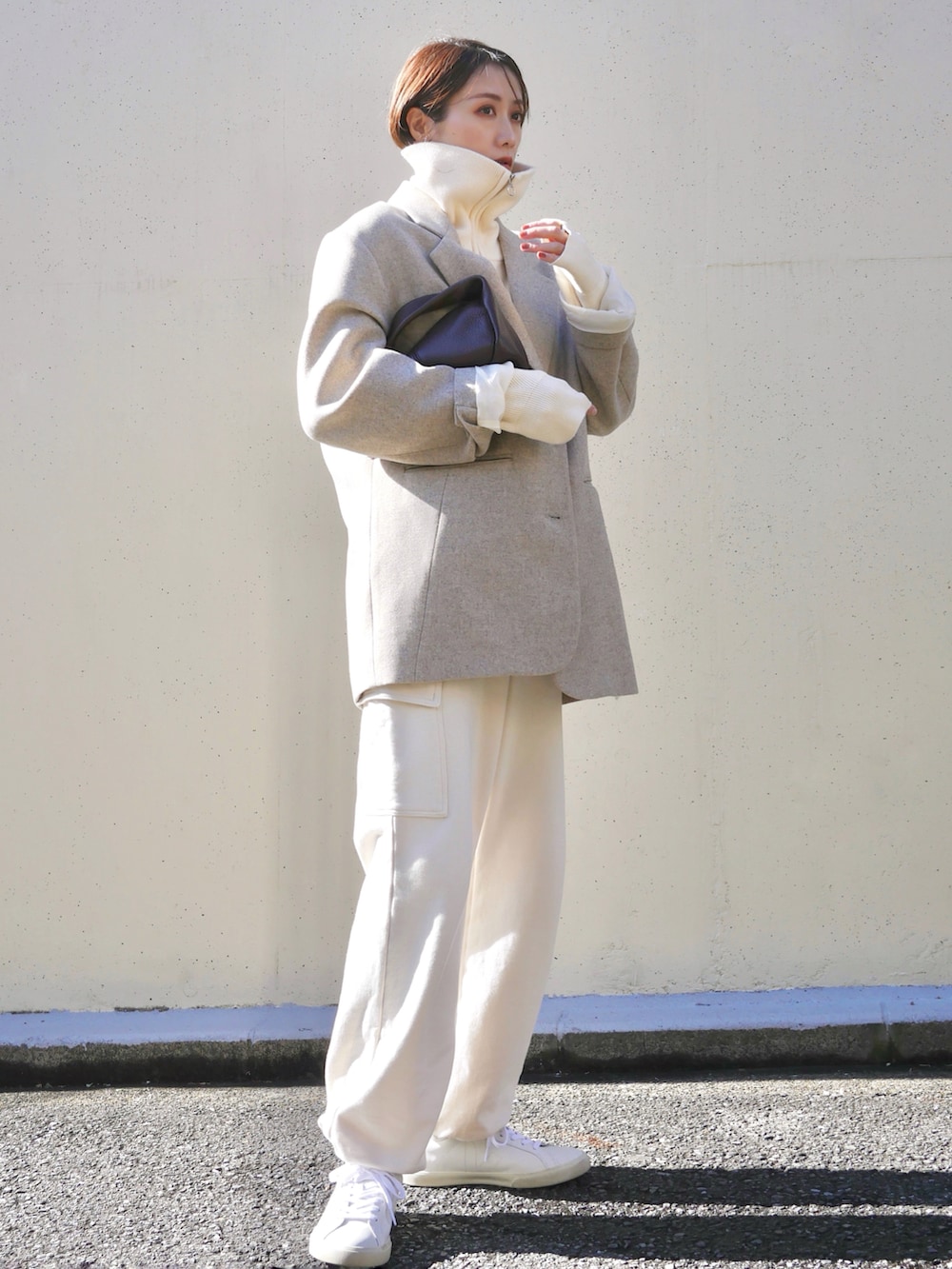 ベージュ系のテーラードジャケット、レッド系のハンドバッグ、ホワイト系のスニーカーを着用したレディースの冬コーディネートの4枚目の写真