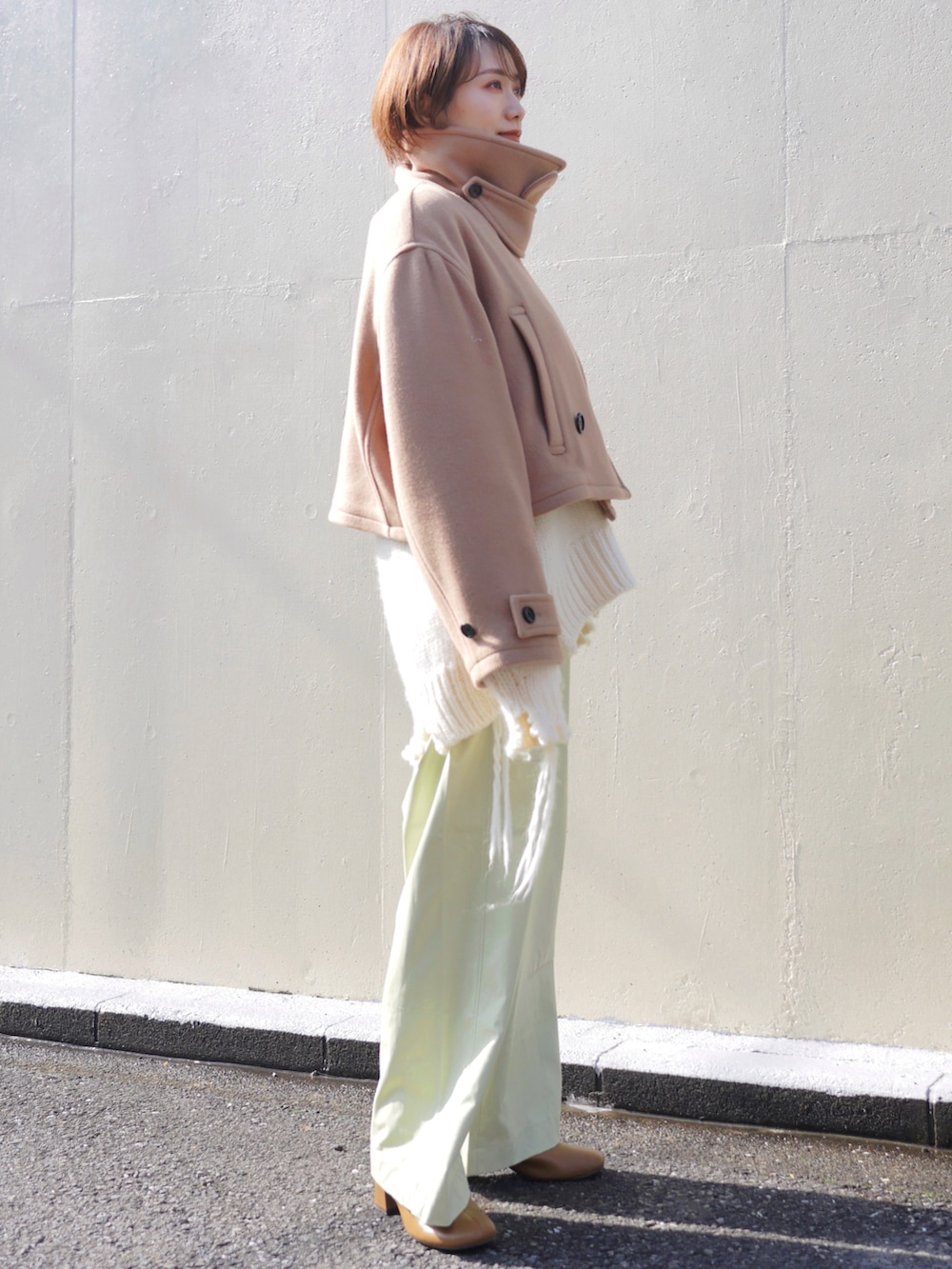 ベージュ系のピーコート、ホワイト系のニット/セーター、グリーン系のその他パンツを着用したレディースの冬コーディネートの4枚目の写真