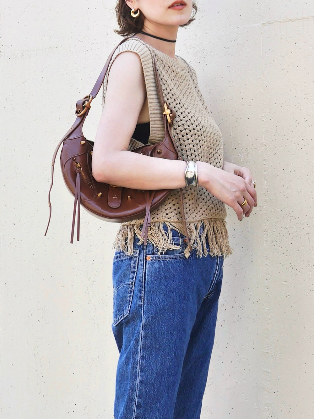 ベージュ系のニット/セーター、ブルー系のデニムパンツ、ブラウン系のバッグを着用したレディースの夏コーディネートの3枚目の写真