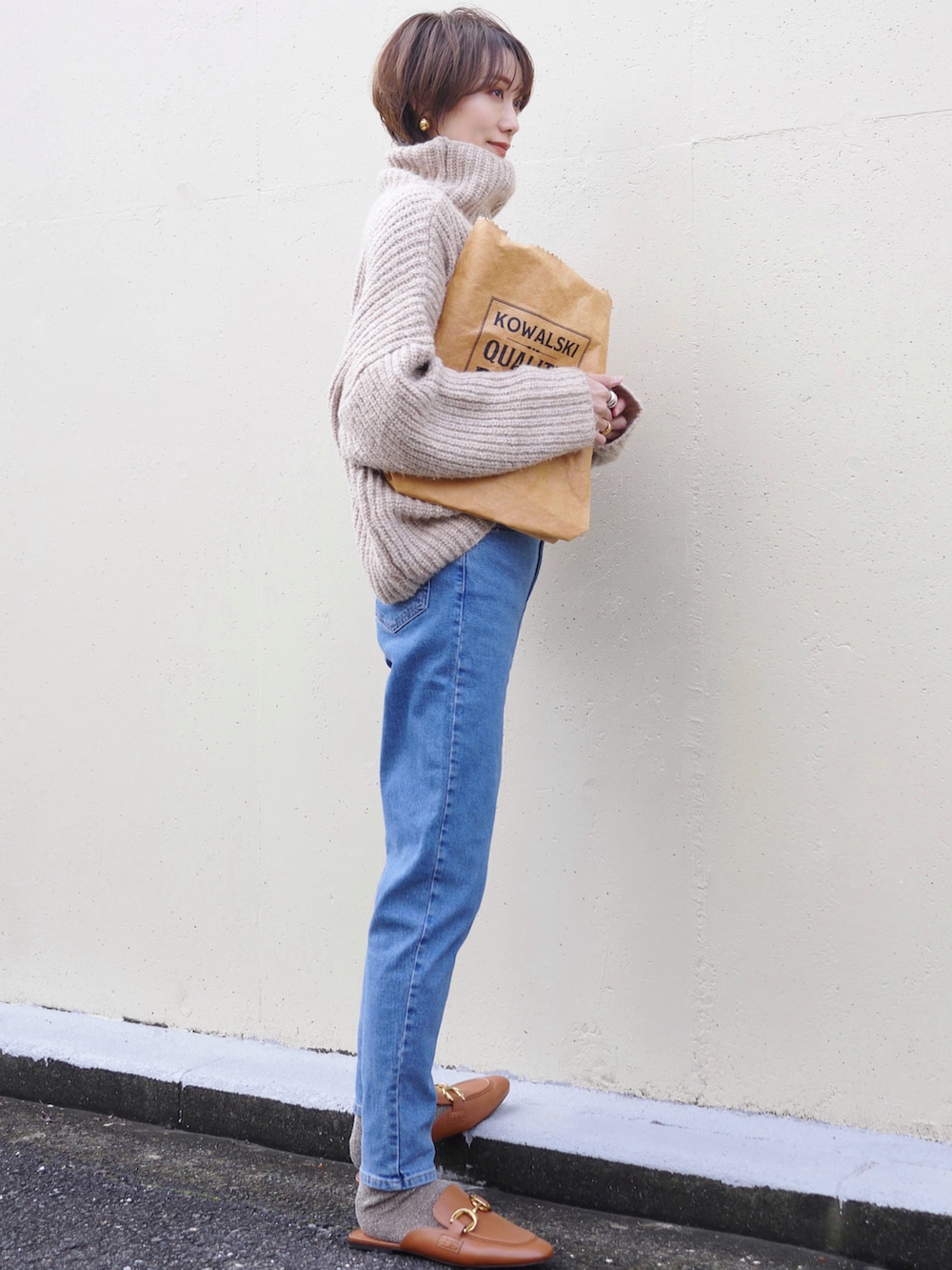 ブルー系のデニムパンツ、ブラウン系のトートバッグ、ベージュ系のニット/セーターを着用したレディースの冬コーディネートの4枚目の写真