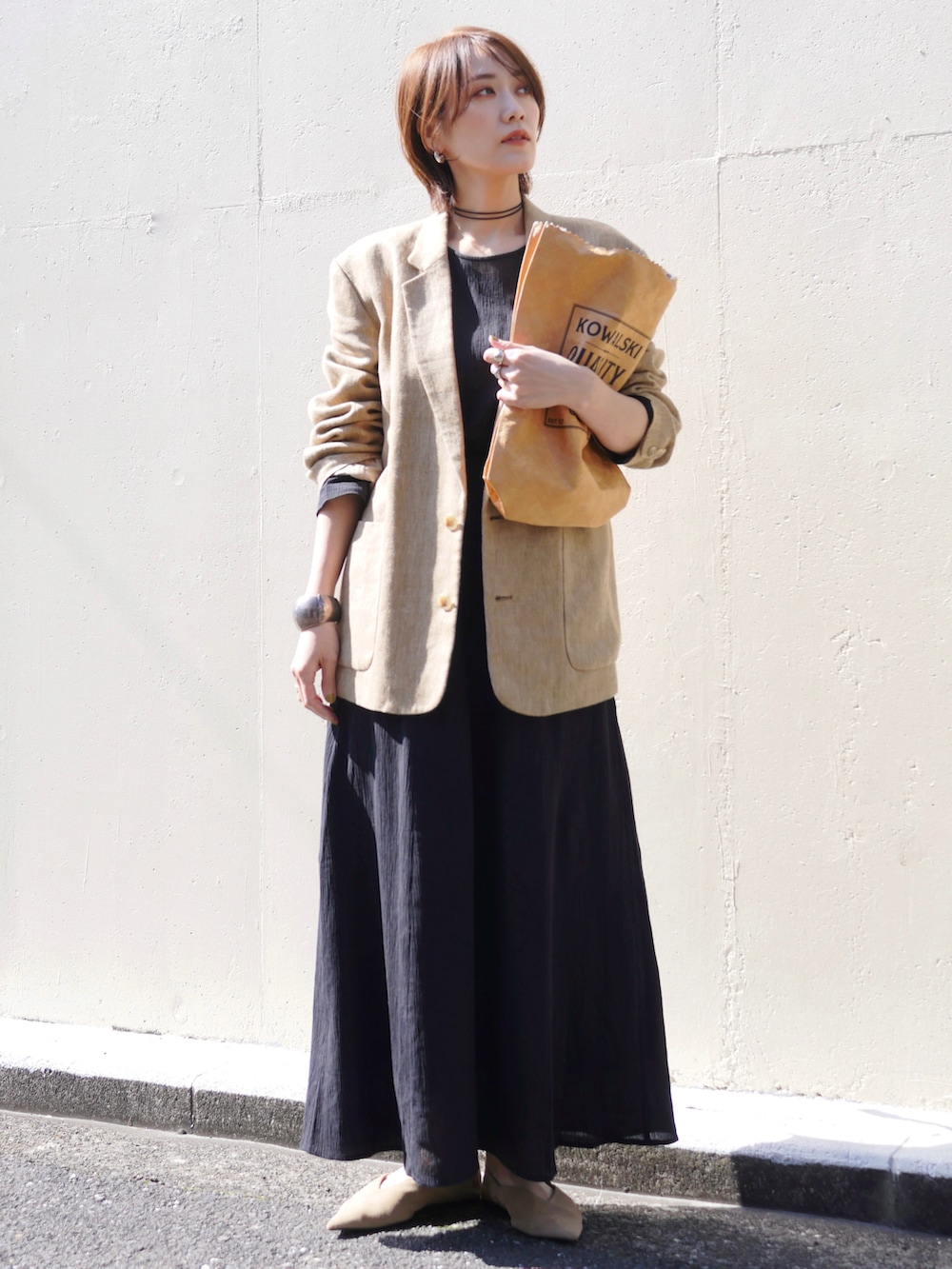 ブラック系のワンピース、ベージュ系のテーラードジャケット、ブラウン系のトートバッグを着用したレディースの春コーディネートの3枚目の写真