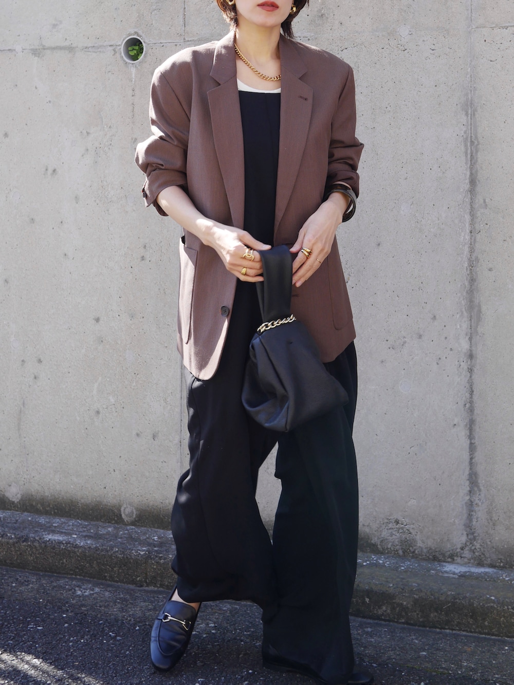 ブラウン系のテーラードジャケット、ブラック系のサロペット/オーバーオール、ブラック系のハンドバッグを着用したレディースの秋コーディネートの4枚目の写真