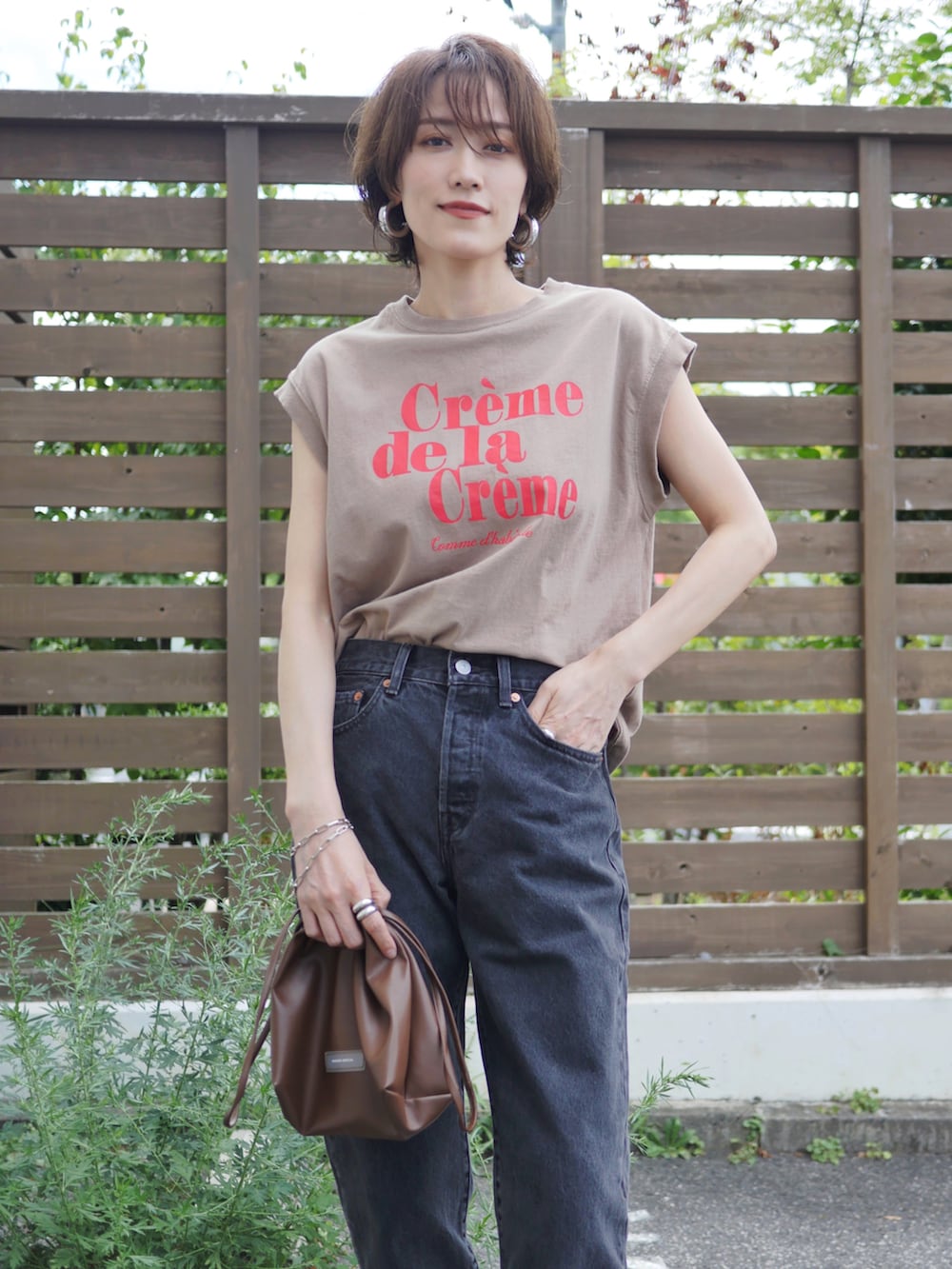 ベージュ系のTシャツ/カットソー、ブラウン系のショルダーバッグ、ブラック系のデニムパンツを着用したレディースの夏コーディネートの2枚目の写真